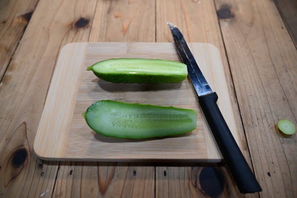 A cucumber sliced in half on a cutting board.