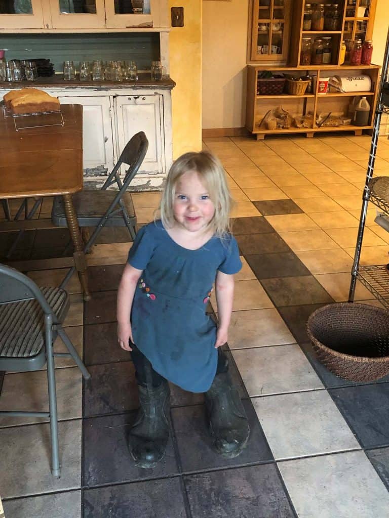 A little girl wearing large Muck boots.