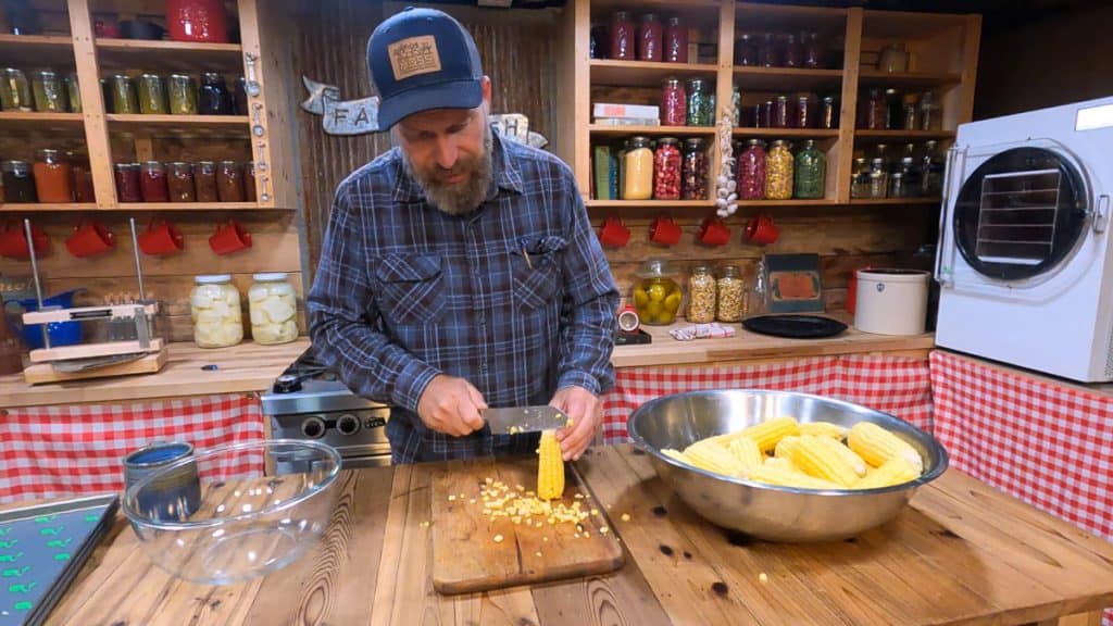 A man cutting corn off a cob.