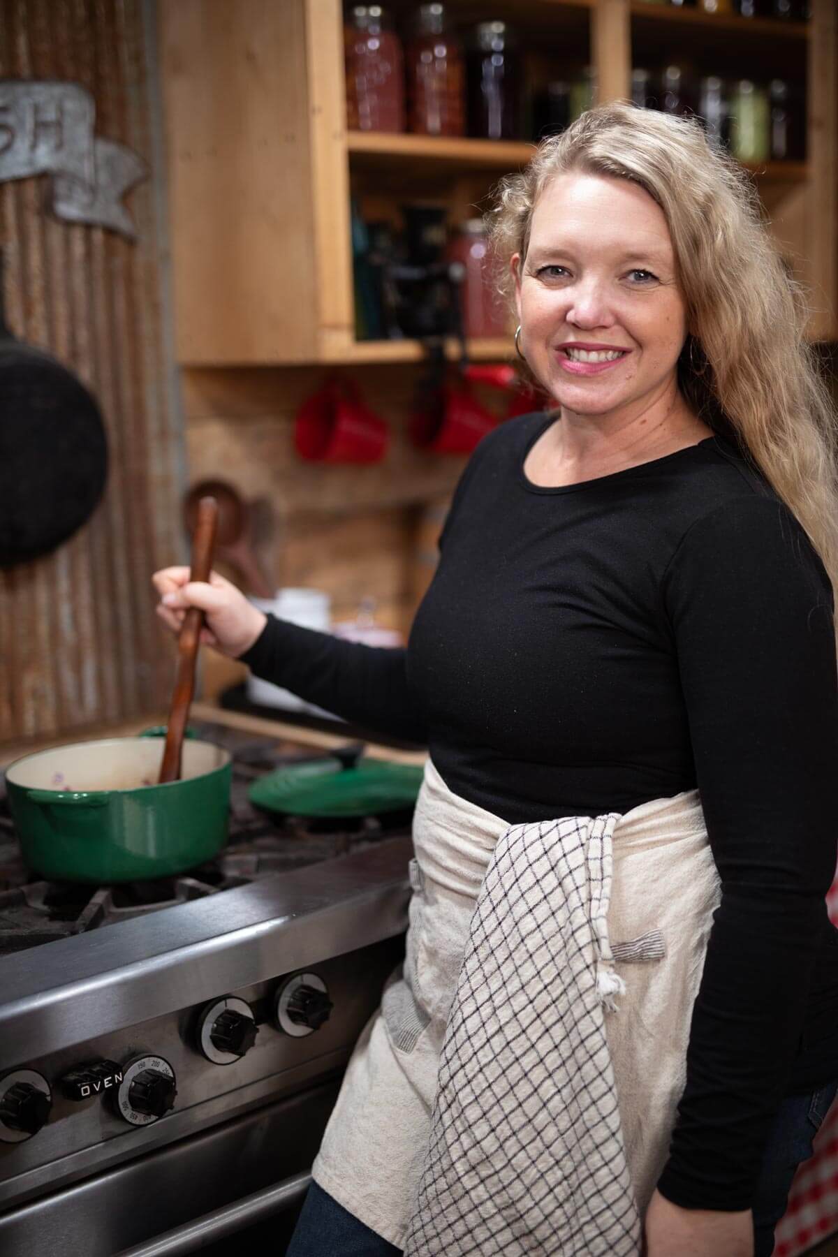 A woman standing at a stove stirring a pot.