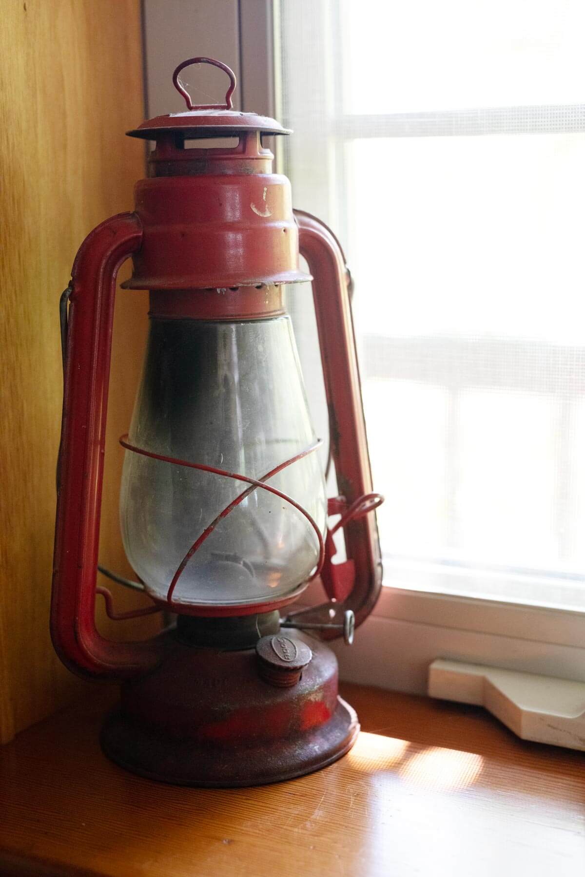 An oil lantern sitting in a windowsill.
