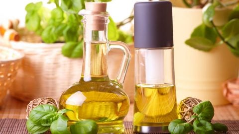 A bottle of oil next to a spray bottle of oil.