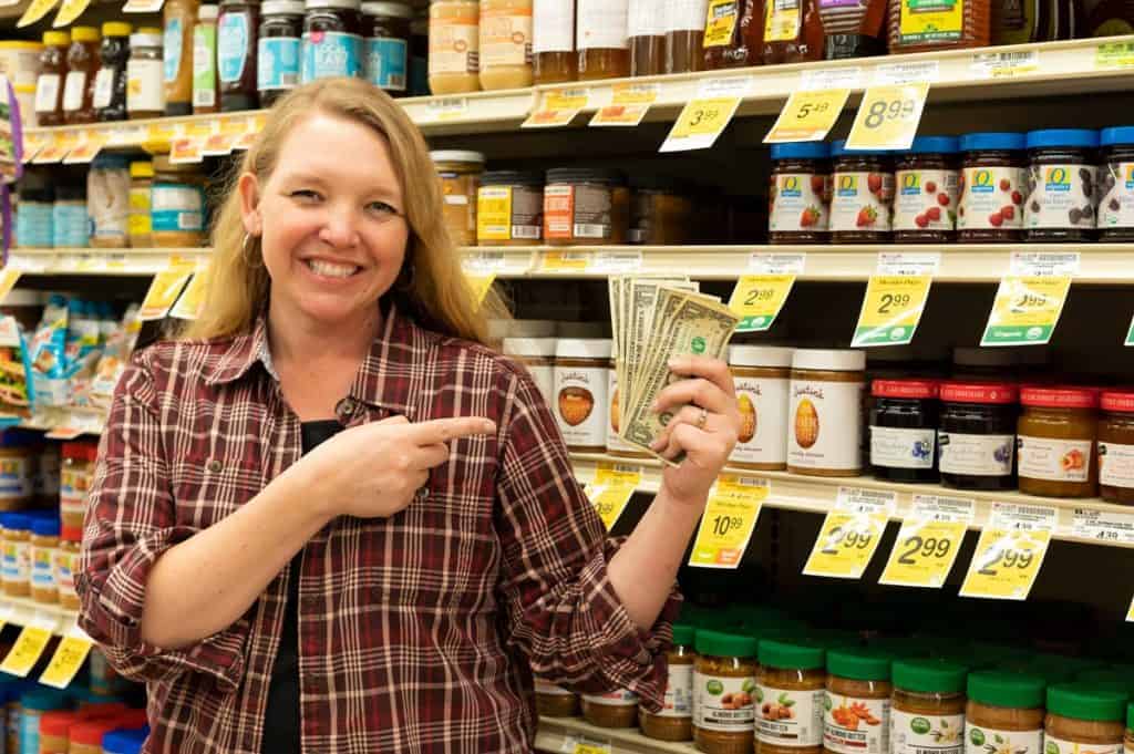 A woman in the grocery store pointing to a handful of money.