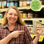 Pinterest pin for how to beat inflation at the grocery store. Image of a woman in a grocery isle holding up a handful of dollar bills.