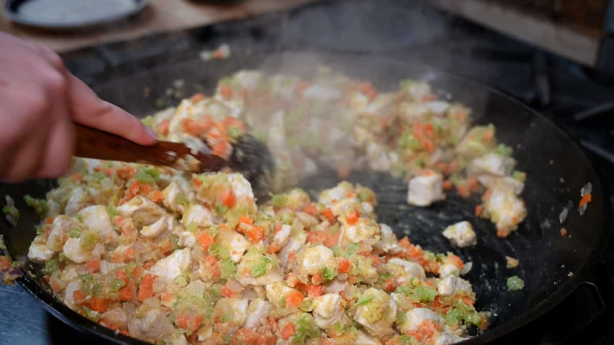 Chicken pot pie filling cooking in a skillet.