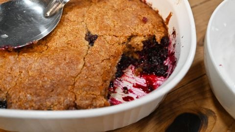 Fruit cobbler in a serving dish with spoon.