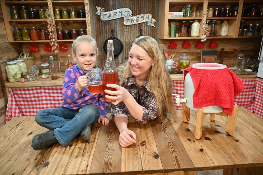 A woman and her daughter clinking their glasses of kombucha together.