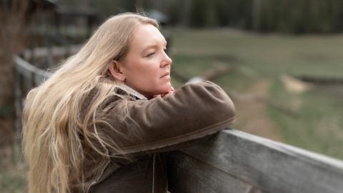 A woman gazing out over a fence.