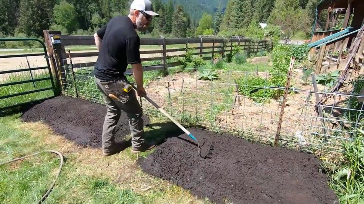 A man raking soil smooth in an instant garden.