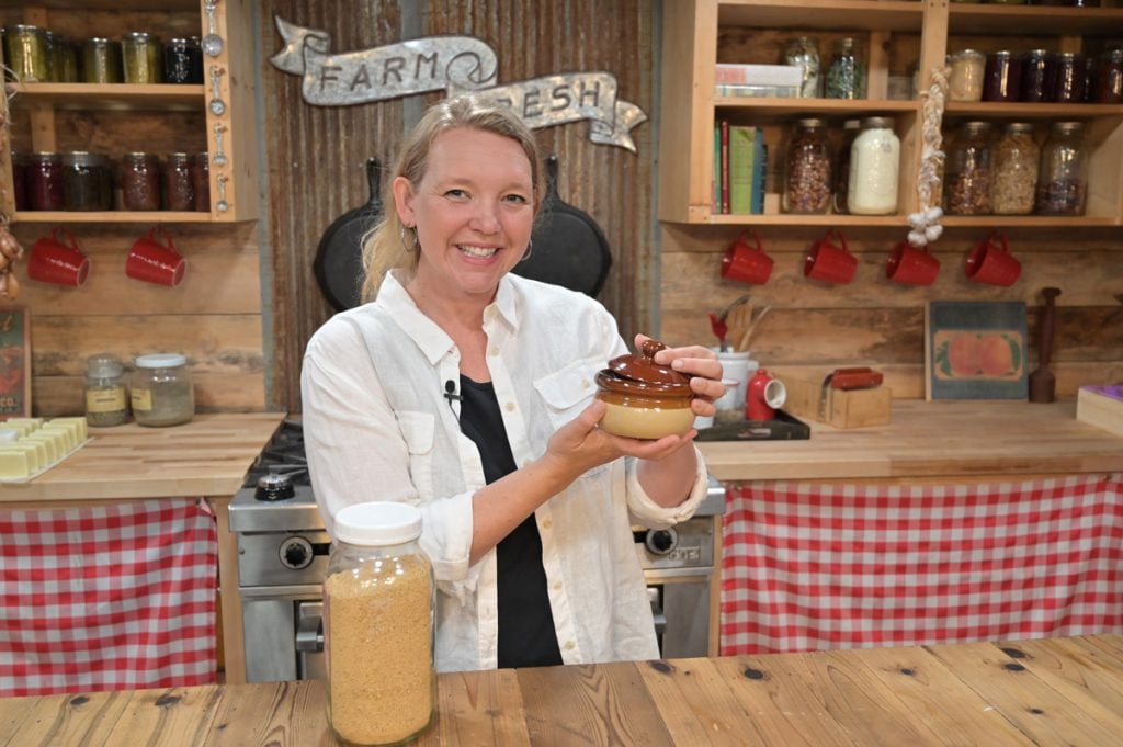 A woman holding a bowl of mustard.