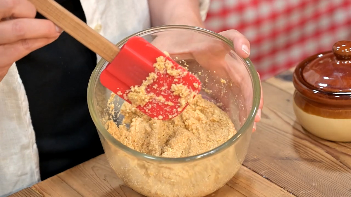 Homemade mustard in a bowl being stirred with a red spatula.