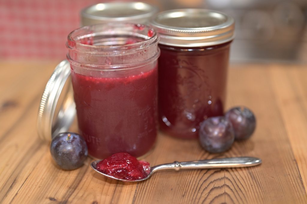 Plum jelly in jars and on a spoon.
