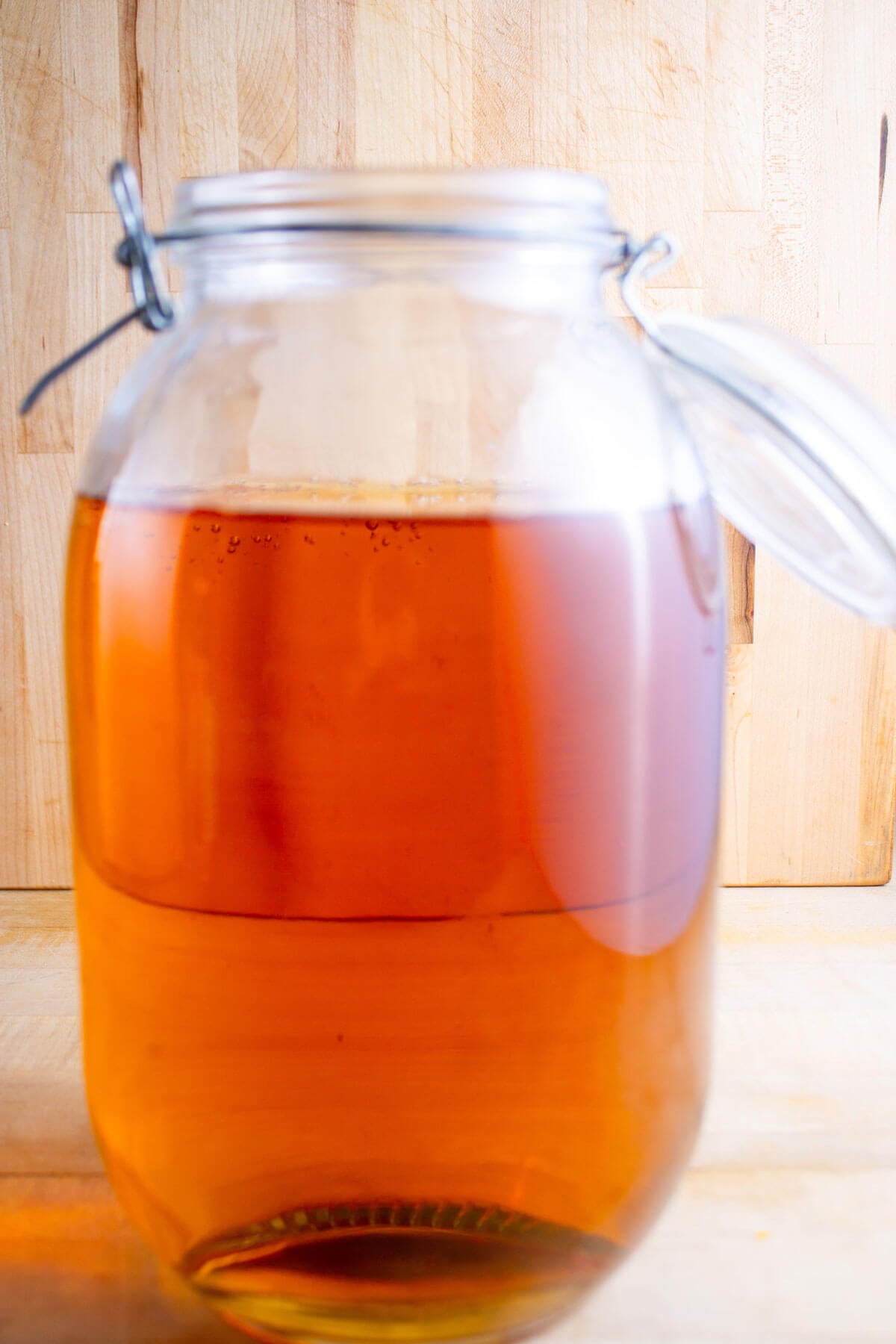 A gallon jar with a flip top lid filled with sparkling apple cider.