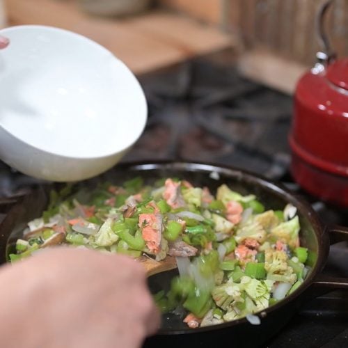 A cast iron pan filled with stir fried vegetables.