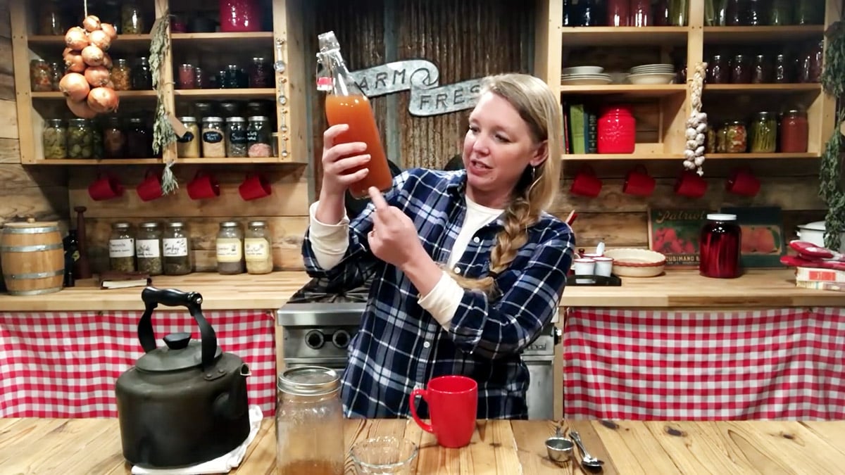 A woman holding up a bottle of apple cider vinegar.