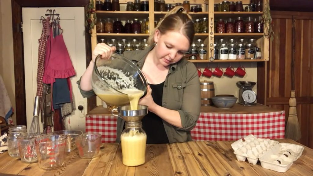 A woman pouring eggnog into a jar.