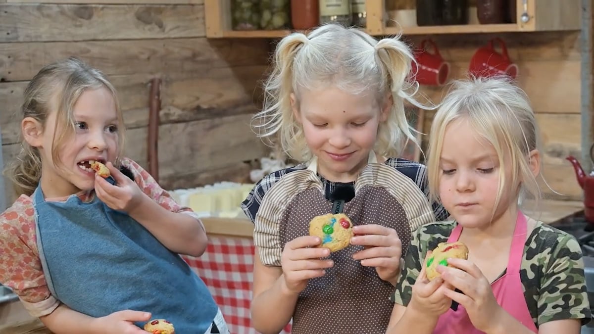 Three young girls eating cookies.