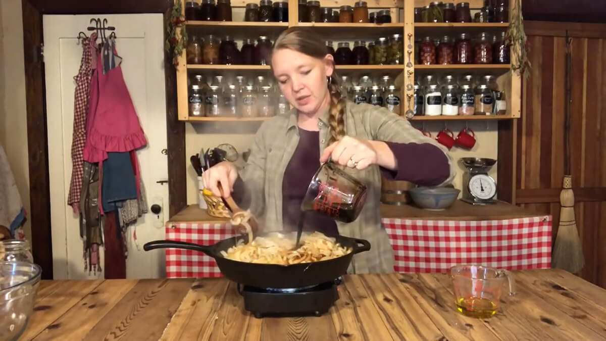 Uma mulher derramando vinagre balsâmico em cebolas caramelizadas.