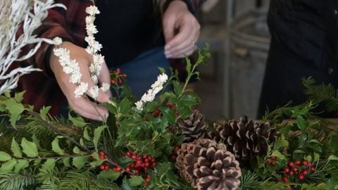 A woman creating a Christmas garland.