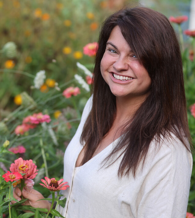 A woman holding a flower standing in a flower field.