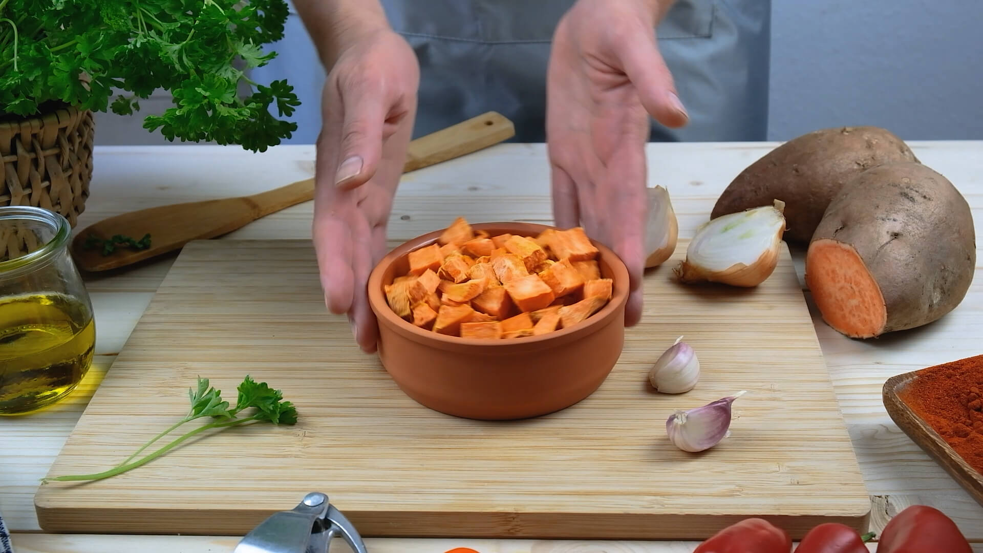 Hands holding a bowl of peeled and chopped sweet potatoes.