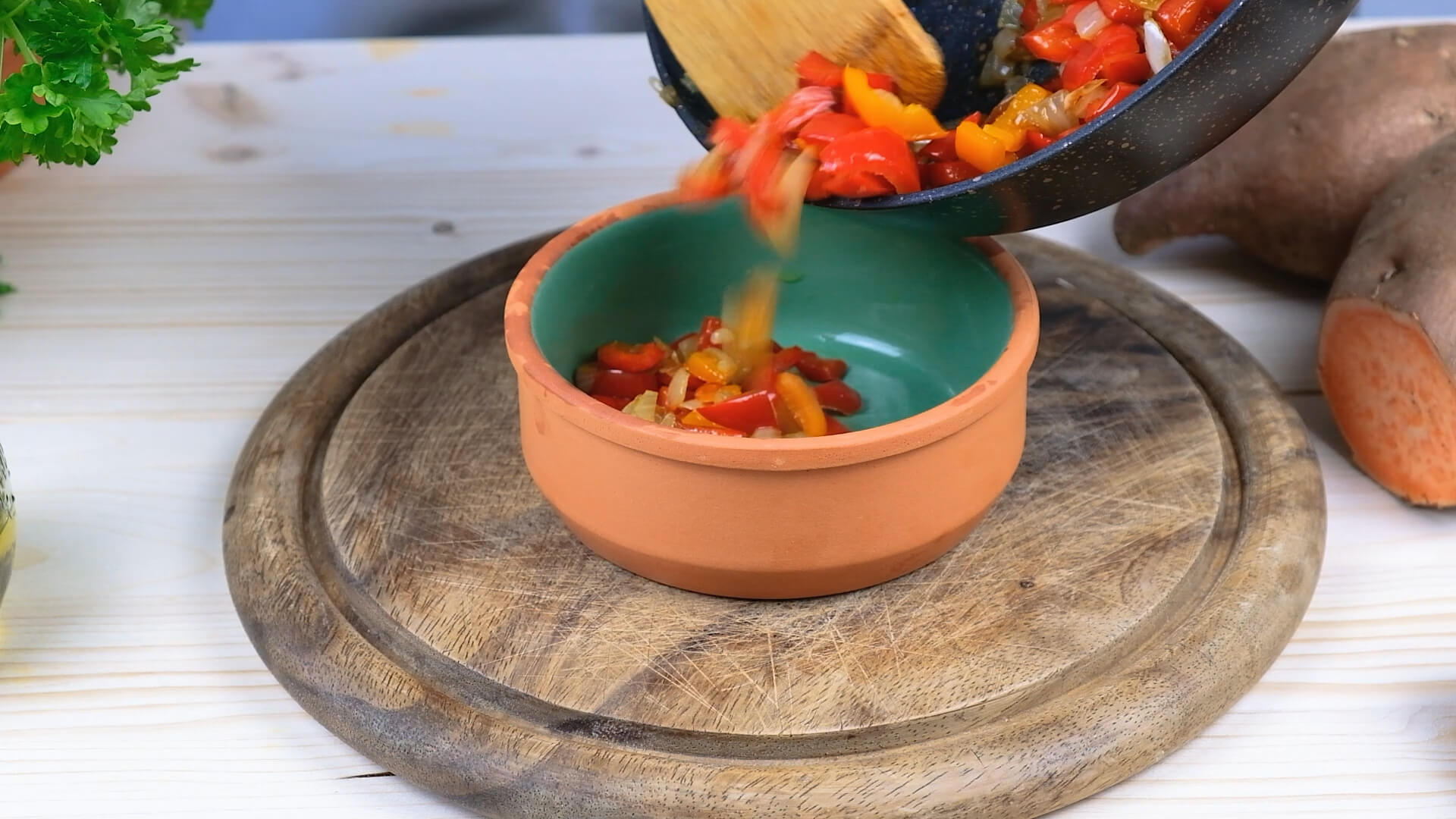 Transferring sauteed peppers and onions from a cast iron skillet to a bowl.