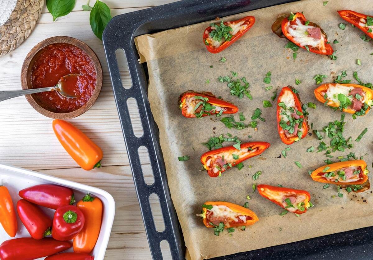 Bird's eye view of bell pepper pizzas on a parchment lined baking sheet.