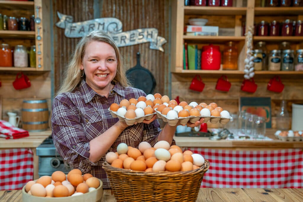 A woman holding up crates of eggs.