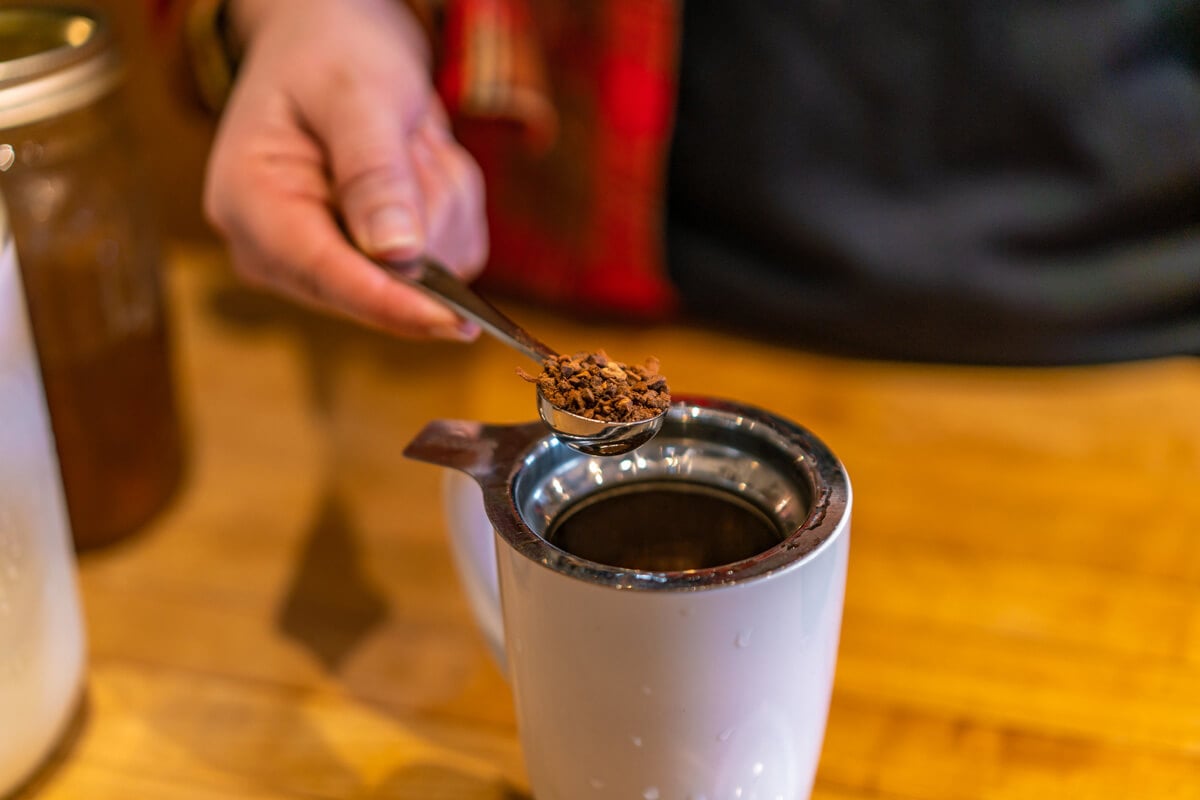 A woman adding loose tea into a mug.