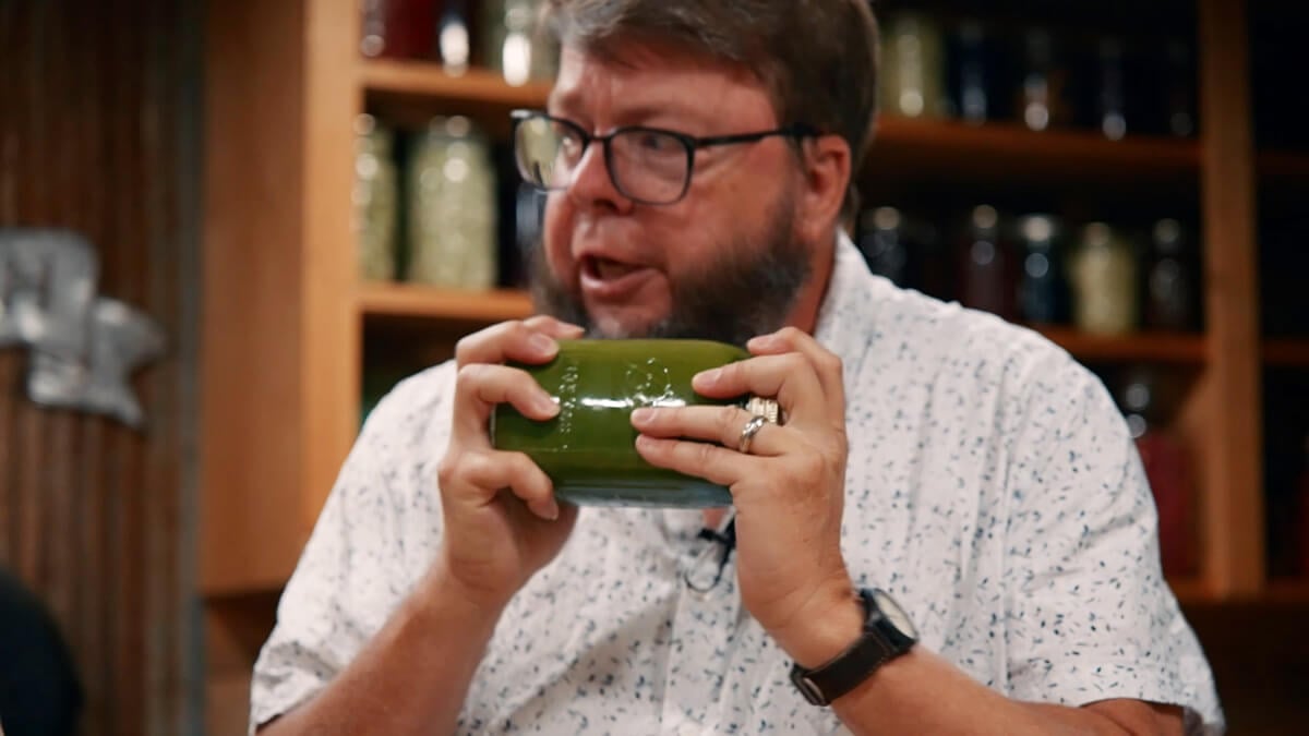 A man shaking a jar of hops tincture.