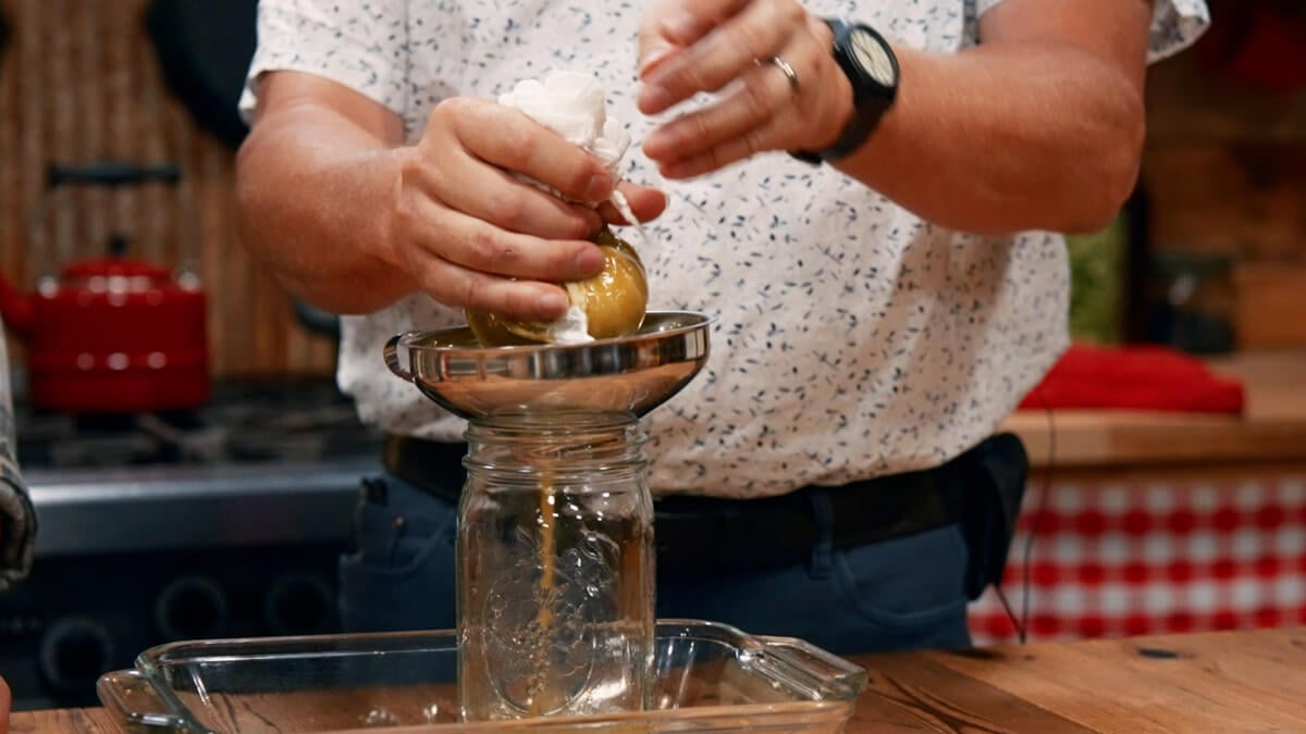 A hops tincture being strained into a jar.