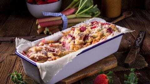 Rhubarb breakfast cake in a loaf pan on a wooden counter.