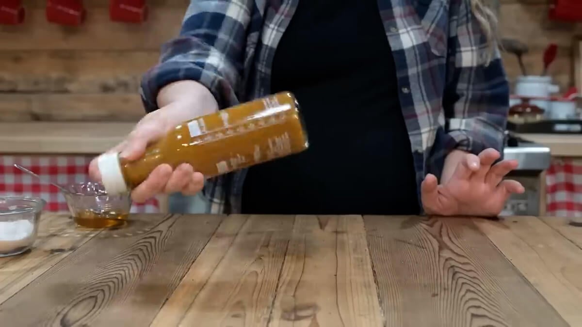 A woman shaking a dressing bottle.