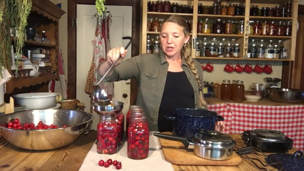 A woman canning cherries in the kitchen.
