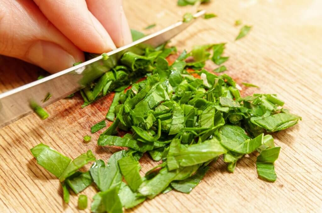 Basil being chopped by a knife.