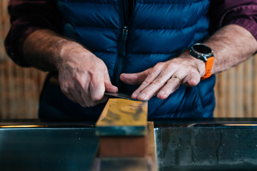 A man sharpening a knife on a stone.