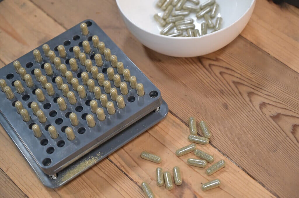 Allergy capsules in a capsule machine and a white bowl.