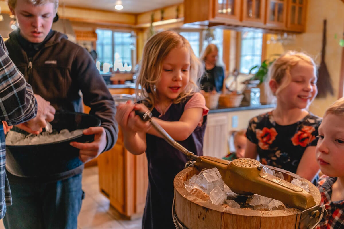 A young girl churning a hand-crank ice cream machine.