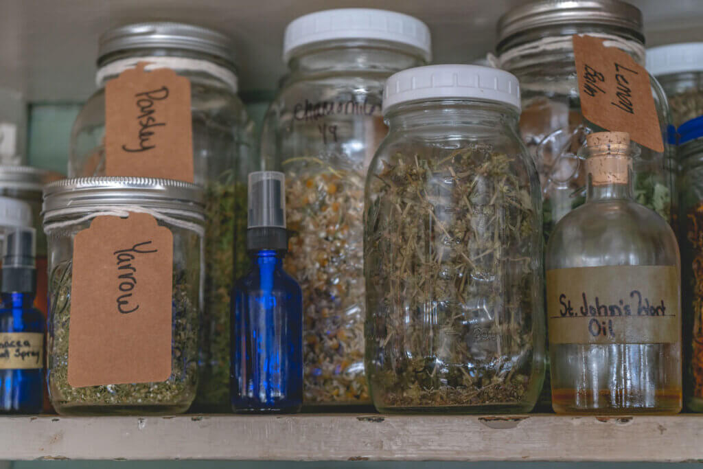 Dried herbs in jars on a shelf.