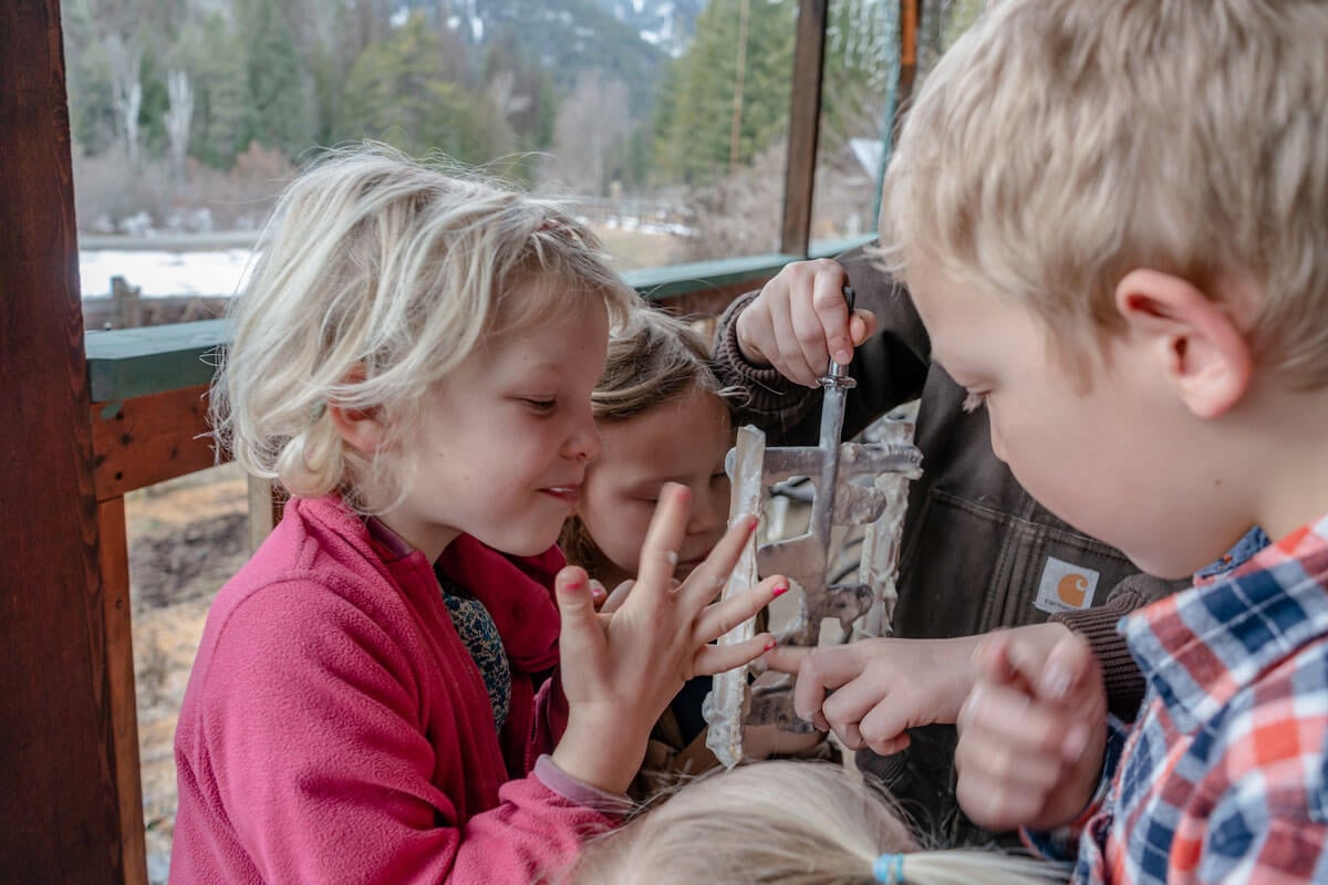 Kids licking the churner of an ice cream machine.