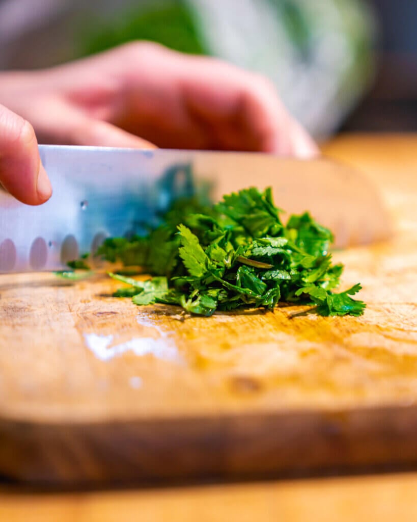 Cilantro being chopped on a cutting board.