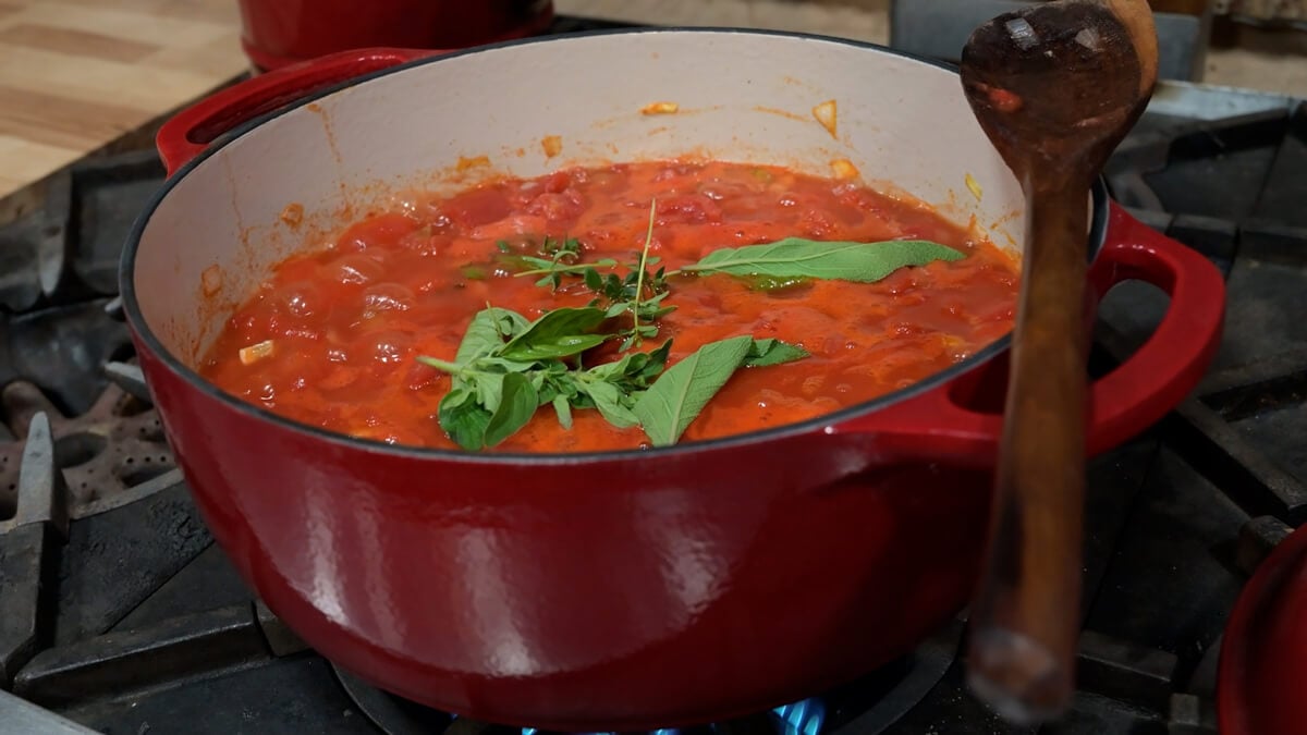 Tomato sauce simmering in an enameled cast iron pan.