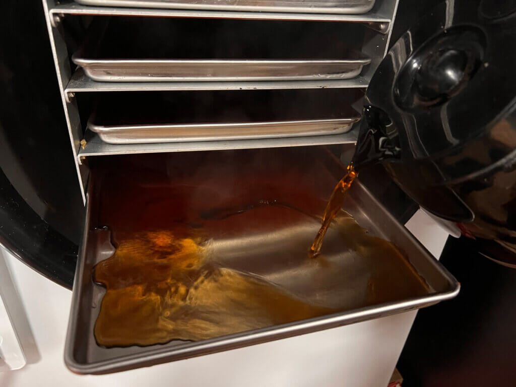Coffee being poured into a tray of a Harvest Right freeze dryer tray.