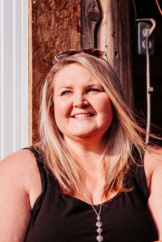 A woman in a black tank top smiling.