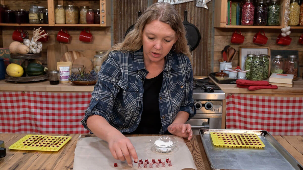 A woman coating elderberry gummies in a sugar mixture.