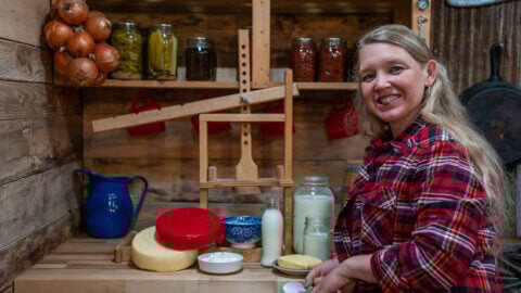 A woman standing beside a counter full of homemade dairy products.