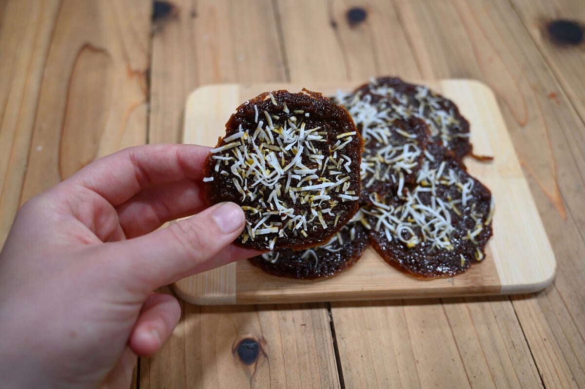 A hand holding a circle of pumpkin fruit leather.