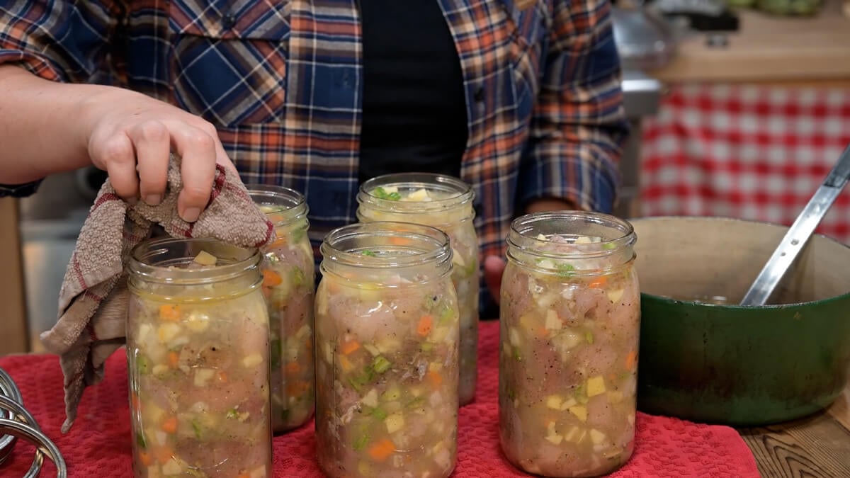 Wiping the rims of jars of chicken and gravy.