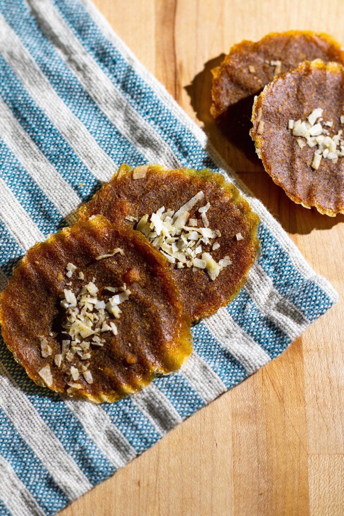 Coconut-topped pumpkin leather rounds resting on a blue-and-white striped towel.