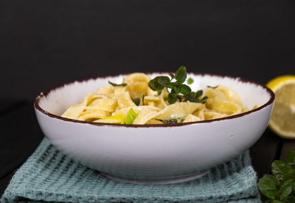 Creamy pasta in a white bowl on a black background.
